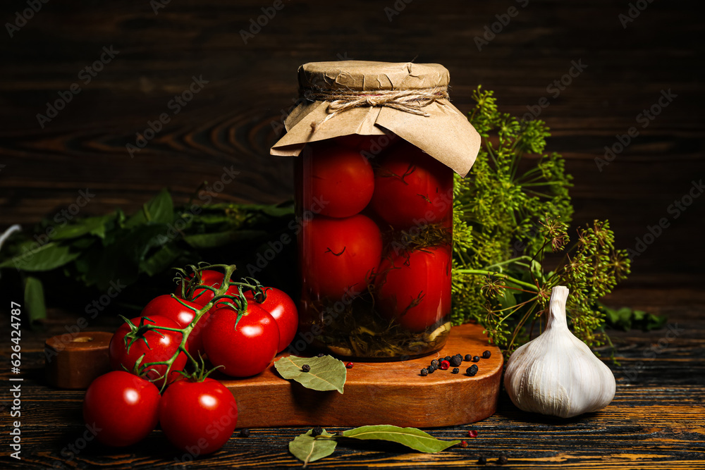 Jar with canned tomatoes and garlic on wooden background