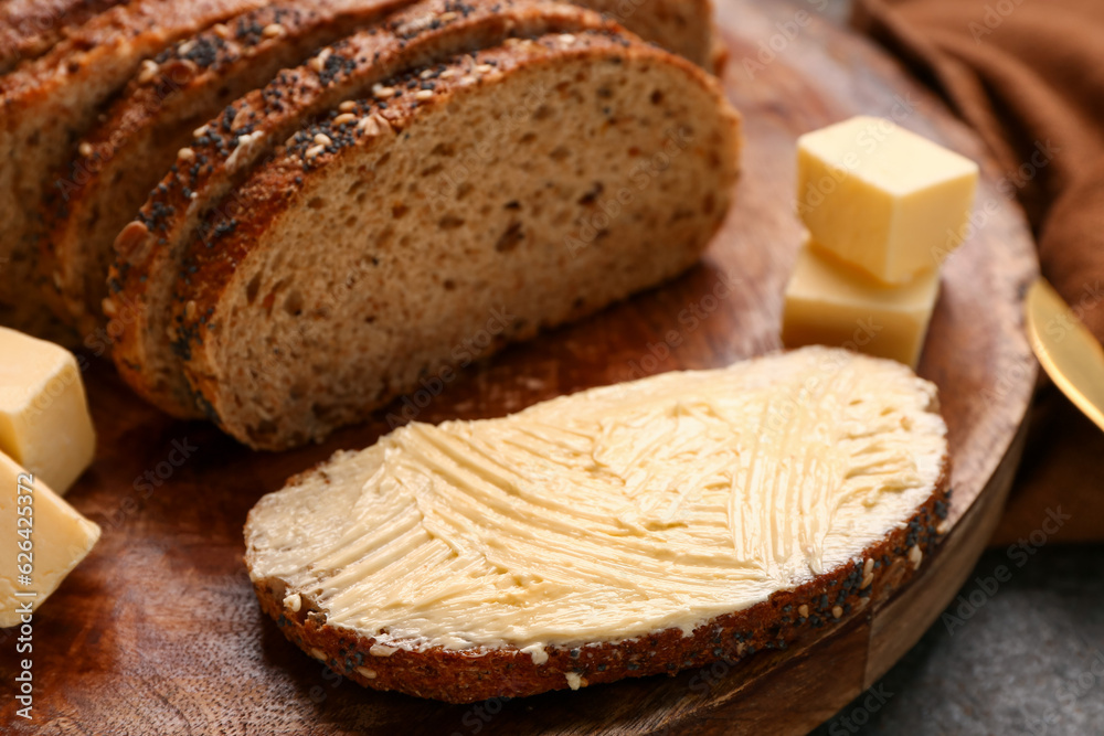 Wooden board with tasty toast with butter on dark background, closeup