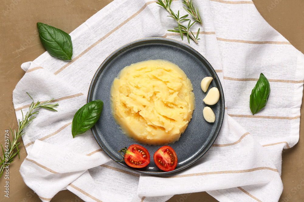 Plate of tasty mashed potatoes with tomato, garlic and basil on brown background