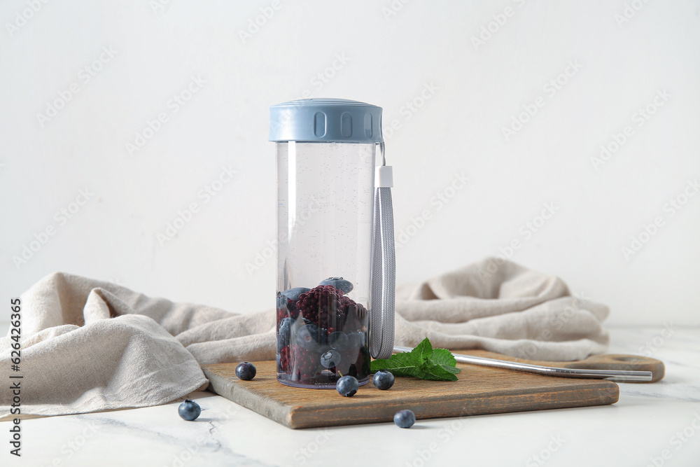 Sports bottle of infused water with blueberries and blackberries on white background