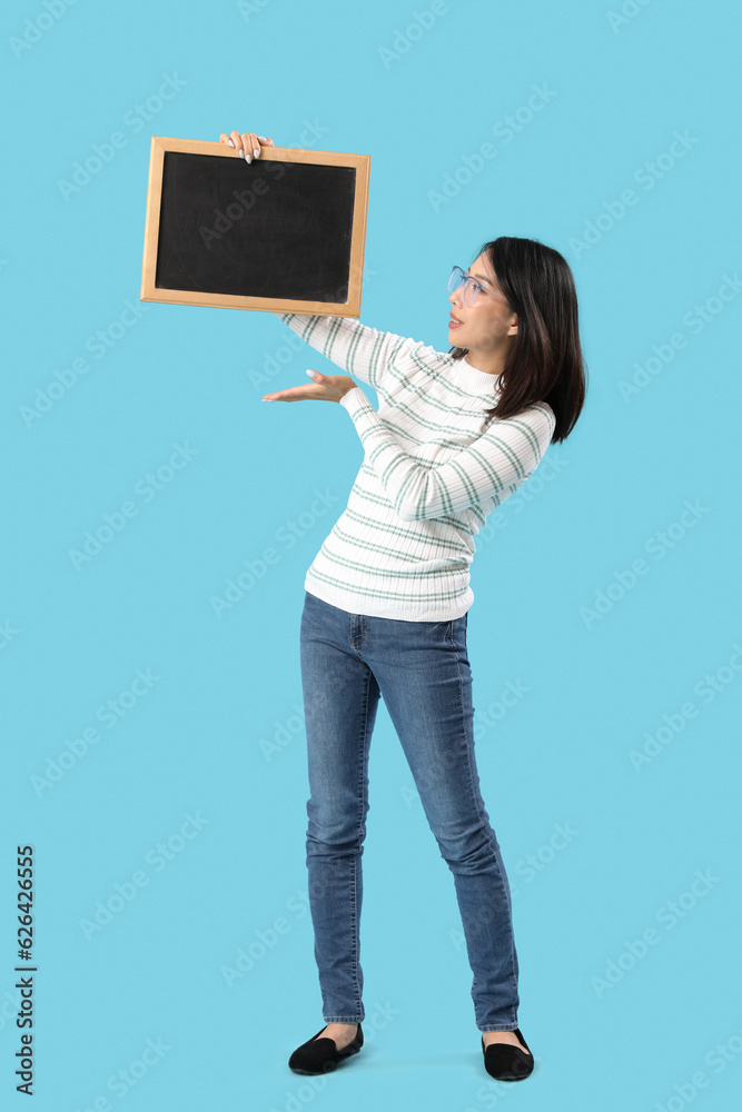 Female Asian teacher with chalkboard on blue background