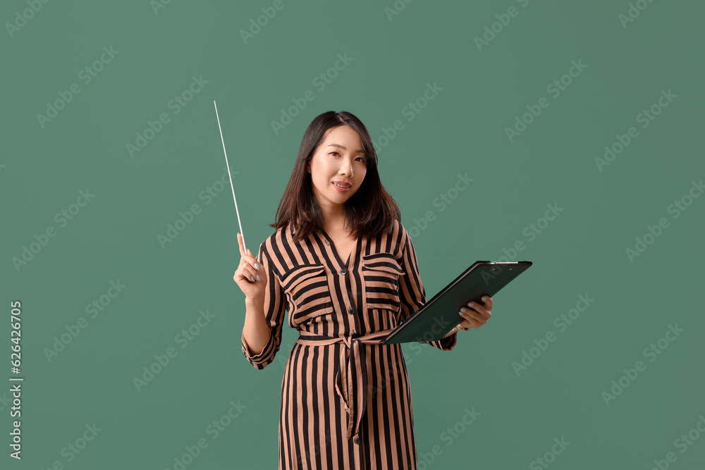 Female Asian teacher with pointer and clipboard on green background