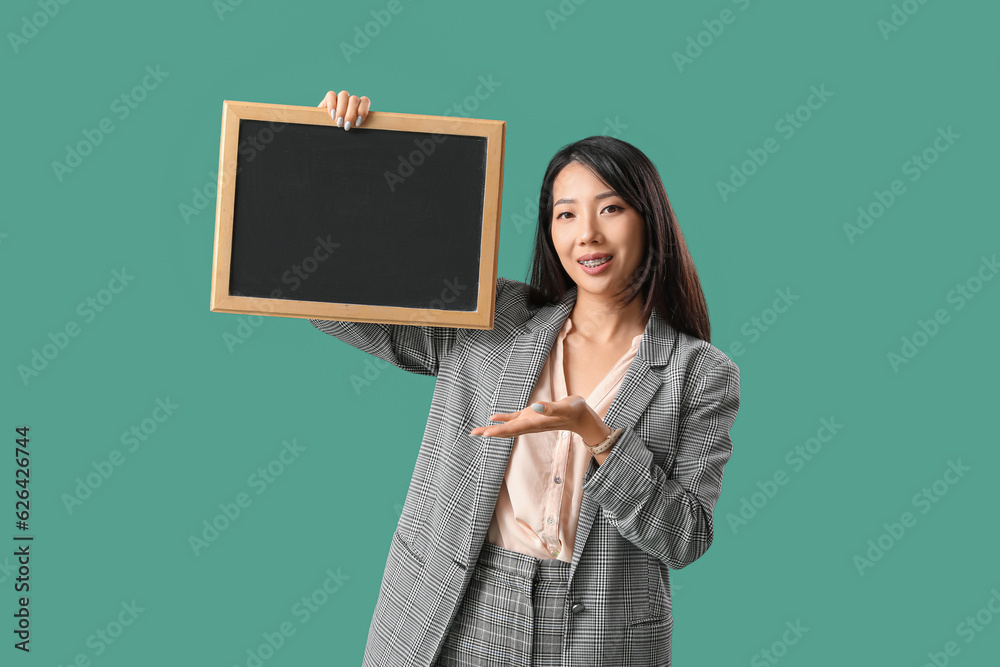 Female Asian teacher with chalkboard on green background