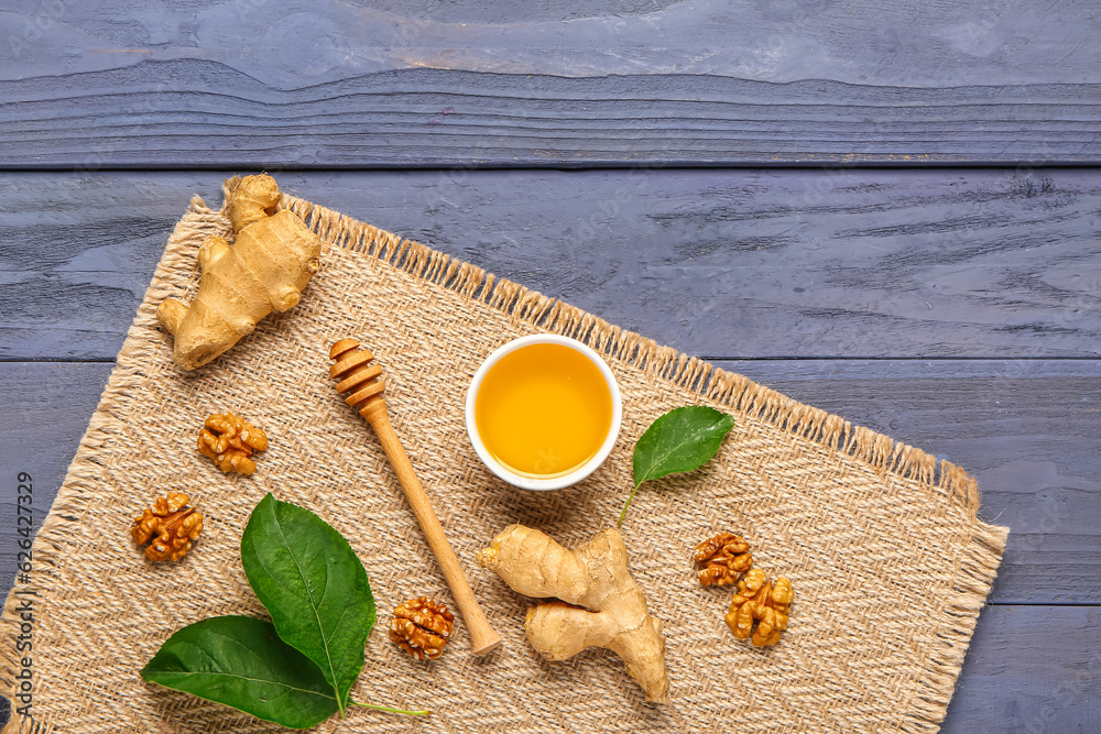 Bowl of sweet honey with walnut and ginger on blue wooden background