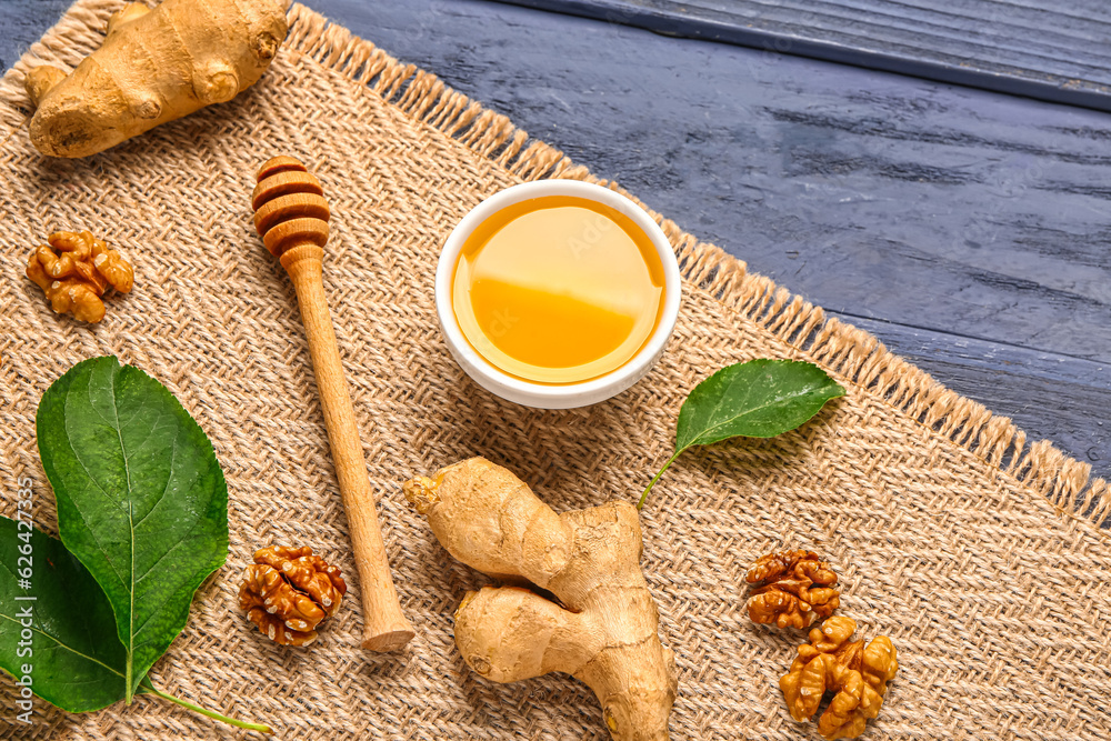 Bowl of sweet honey with walnut and ginger on blue wooden background