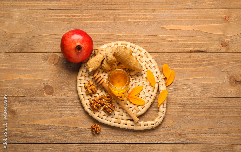 Jar of sweet honey with walnut, ginger and pomegranate on wooden background