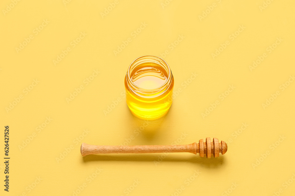 Jar of sweet honey and dipper on yellow background