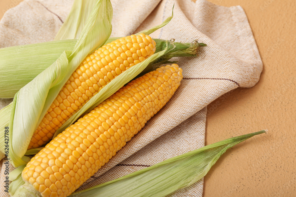 Fresh corn cobs on brown background