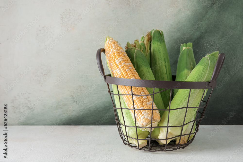 Basket with fresh corn cobs on table