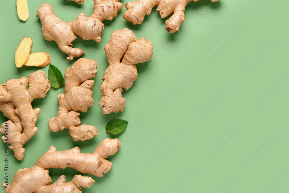 Fresh ginger roots and leaves on green background