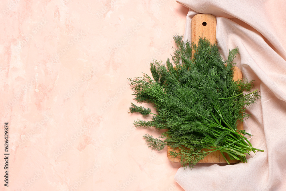 Wooden board with fresh dill on pink background