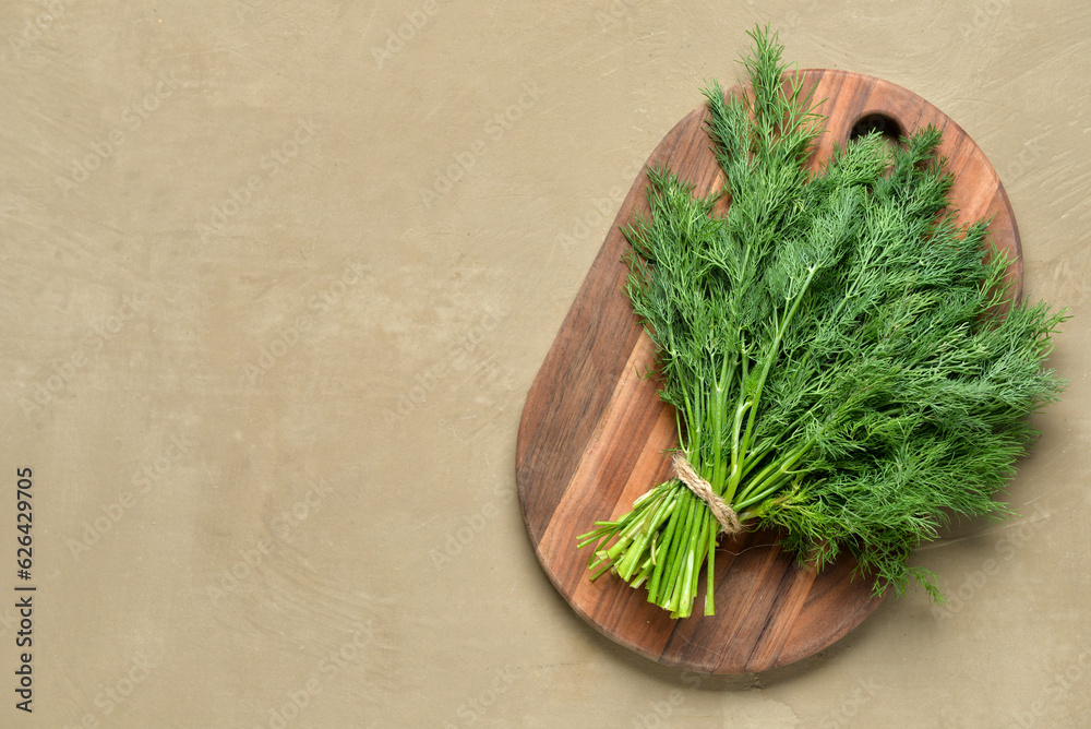 Wooden board with bunch of fresh dill on grey background