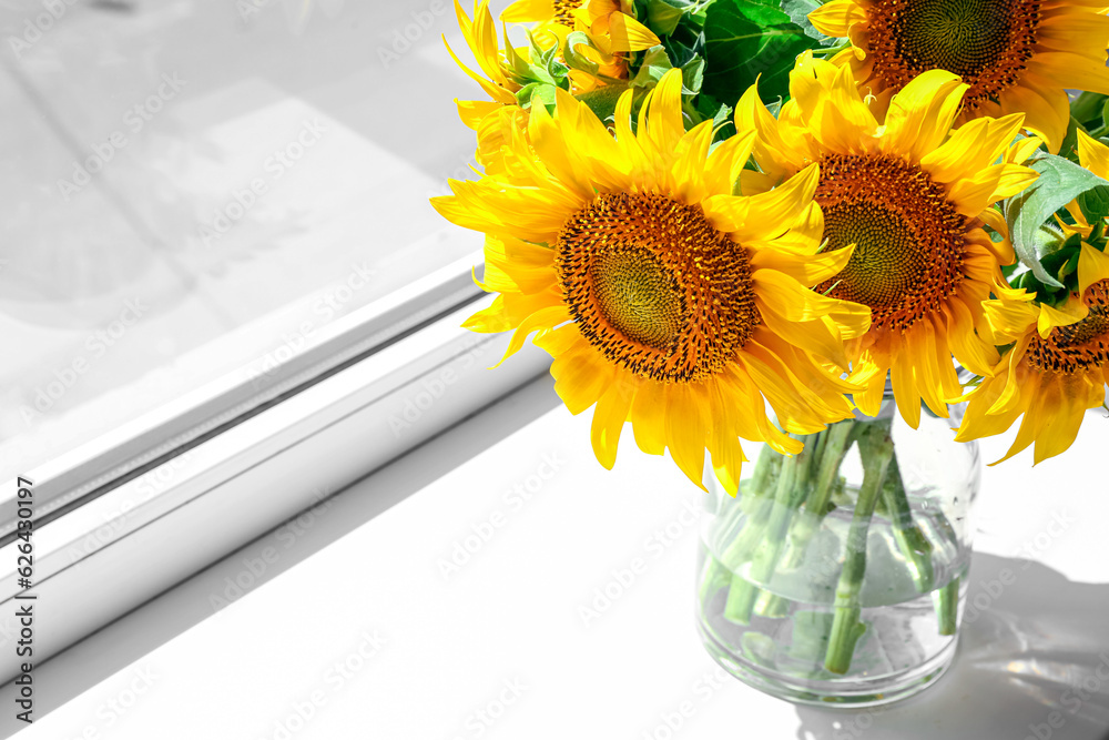 Vase with beautiful sunflowers on windowsill in room, closeup