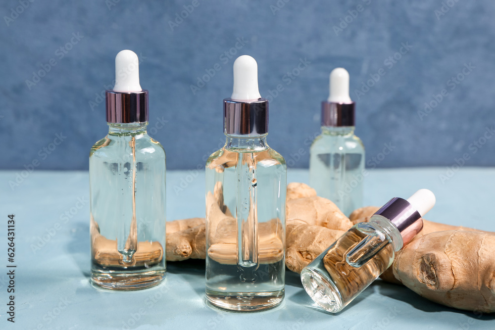 Bottles of ginger cosmetic oil on blue background