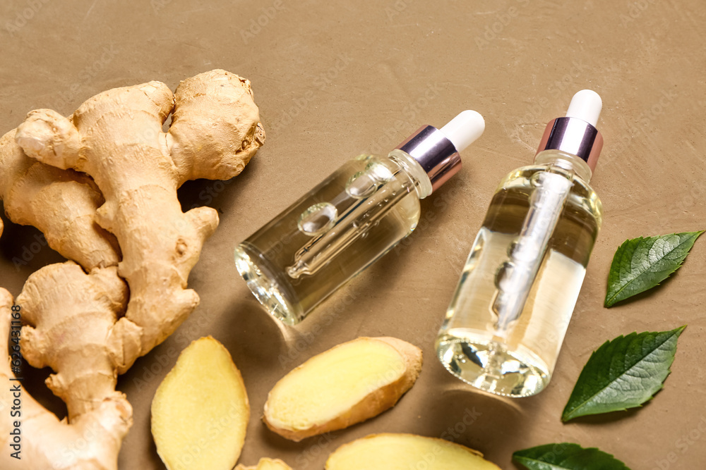 Bottles of ginger cosmetic oil and leaves on brown background