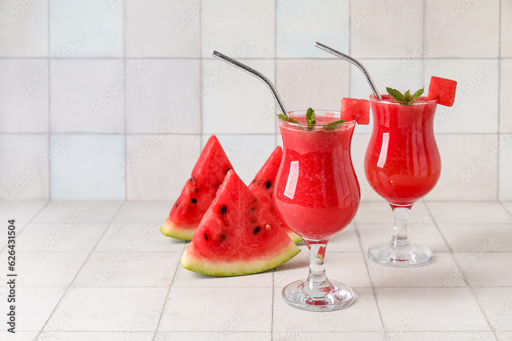 Glasses of tasty watermelon juice with mint on white tile background