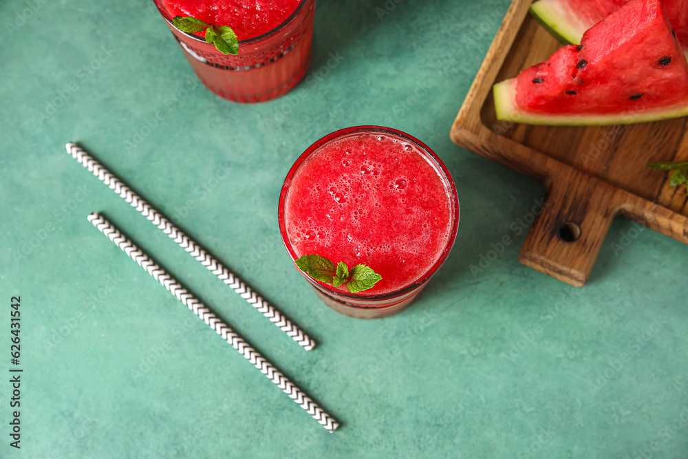 Glass of tasty watermelon juice with mint on green table