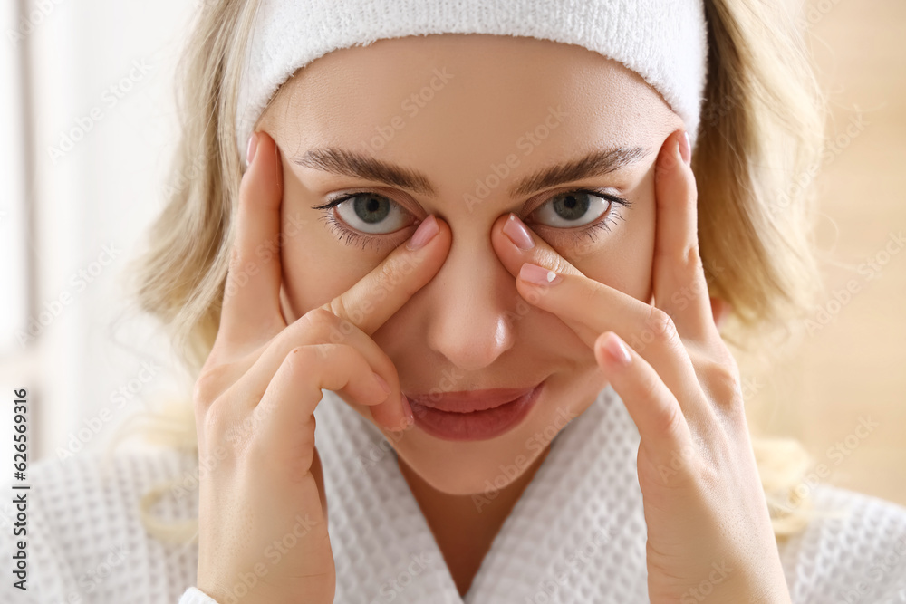 Young woman doing face building exercise in bathroom, closeup