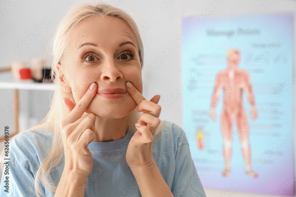 Mature physiotherapist doing face building exercise in rehabilitation center, closeup