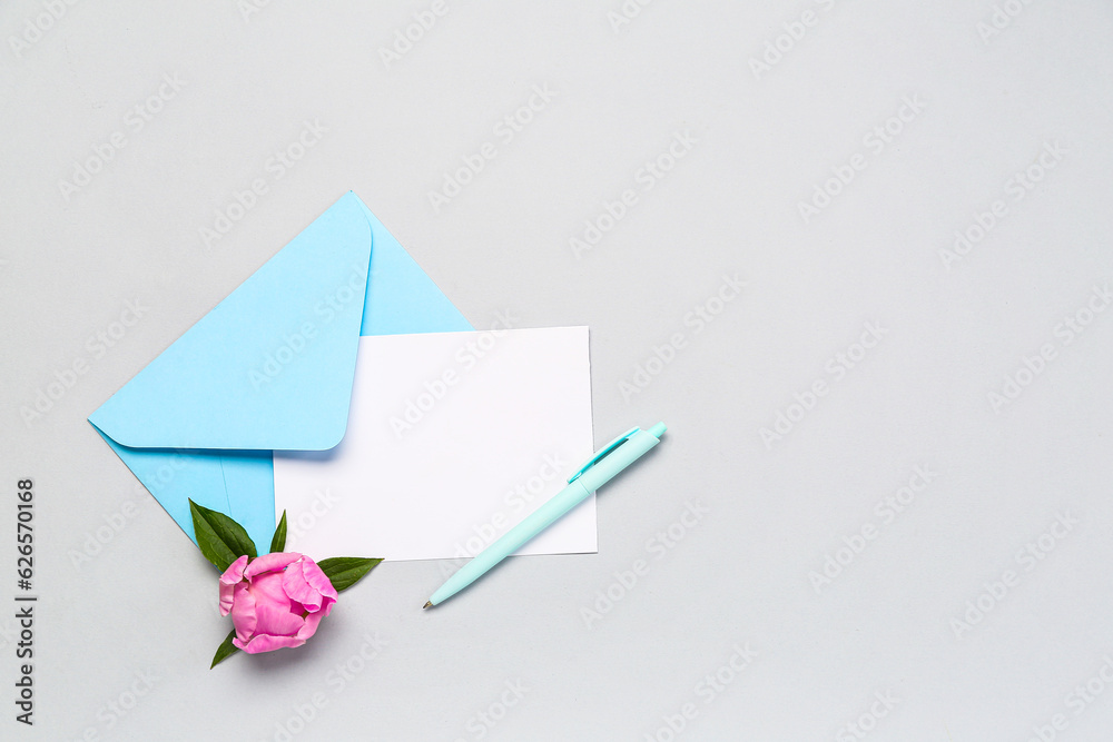 Blank card, envelope, pen and peony flower on light background