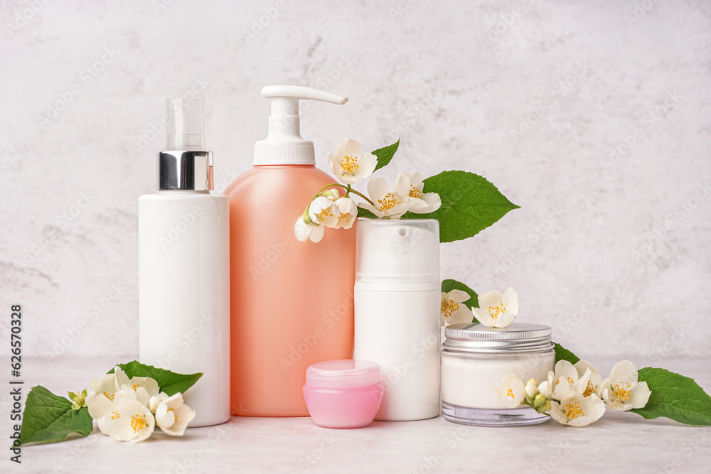 Set of cosmetic products with beautiful jasmine flowers on light background