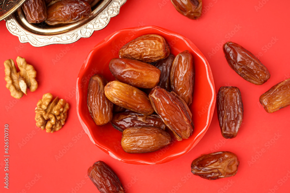 Bowls with dried dates on red background