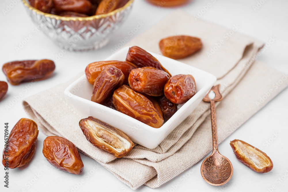 Bowl with dried dates on light background