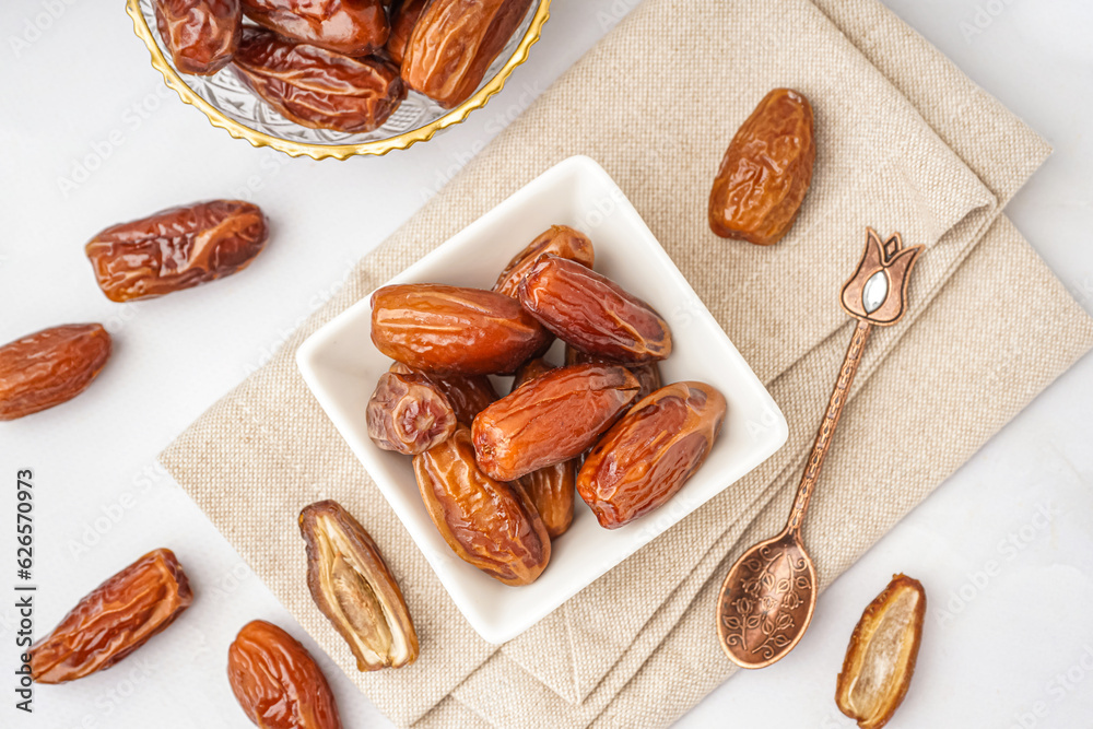 Bowls with dried dates on light background