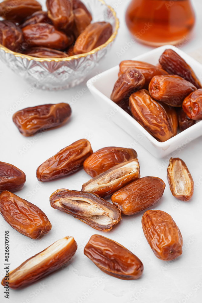 Bowls with dried dates on light background