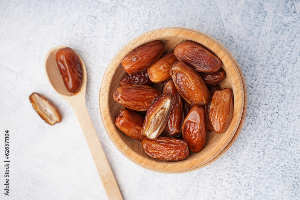 Bowl with dried dates on light background