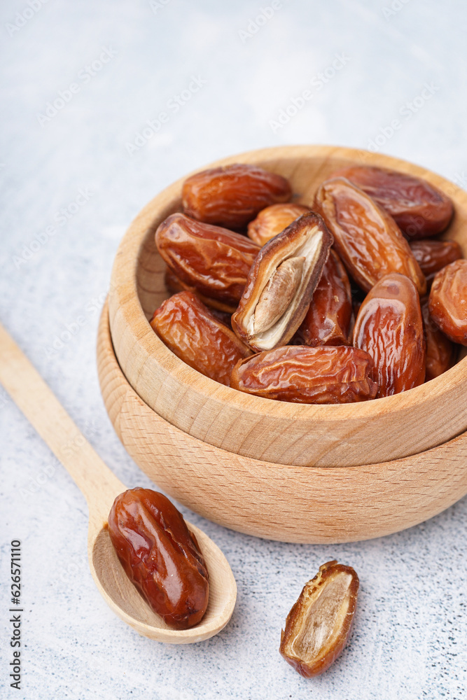 Bowls with dried dates on light background