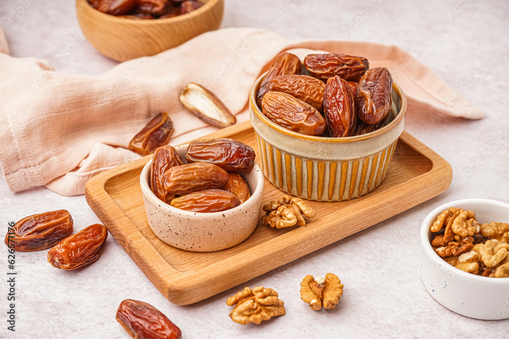 Bowls with dried dates on light background