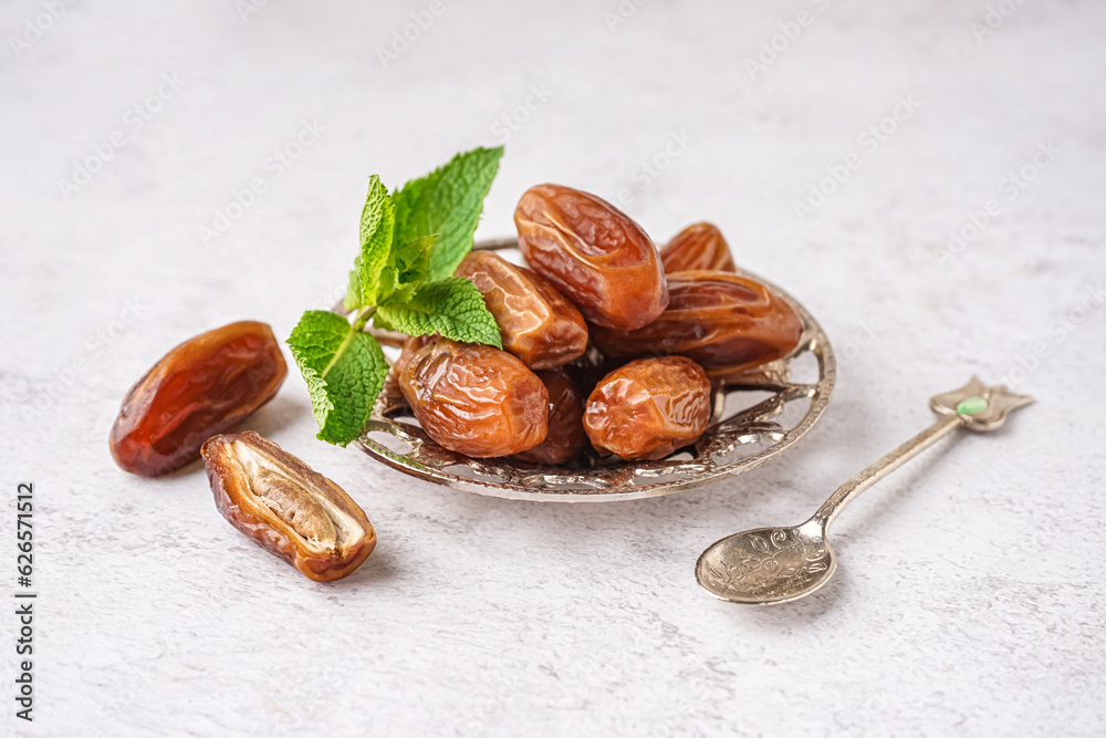 Bowl with dried dates on light background