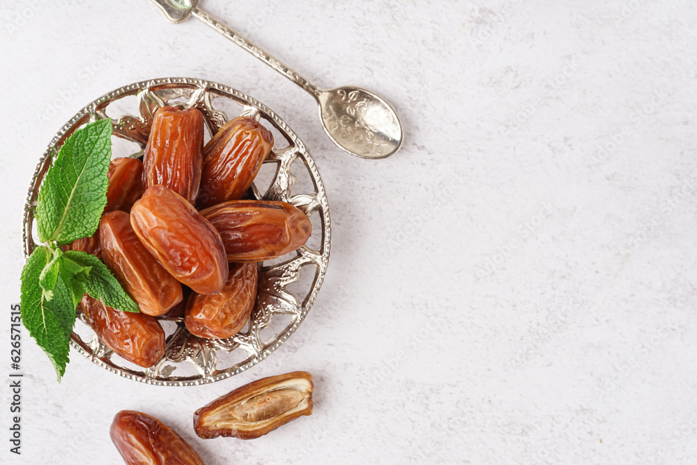 Bowl with dried dates on light background