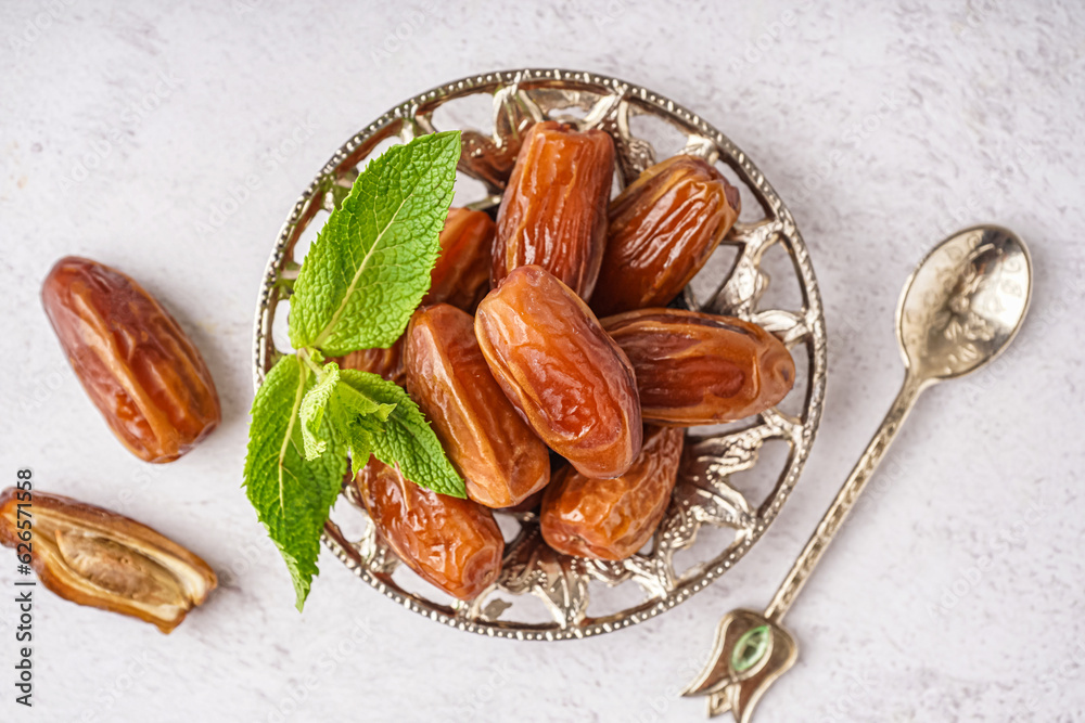 Bowl with dried dates on light background