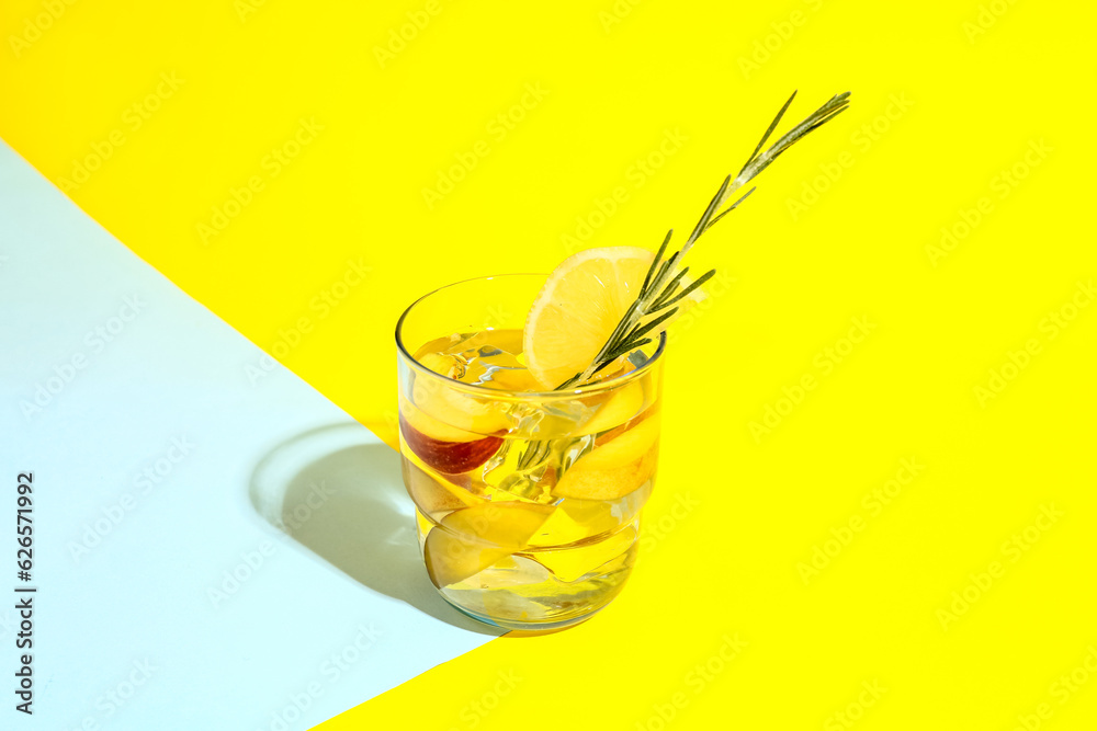 Glass of fresh peach lemonade with rosemary on colorful background