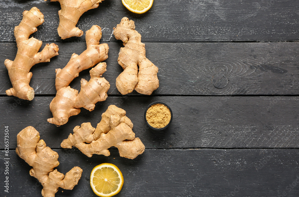 Fresh ginger roots with lemon and bowl of dried powder on black wooden background