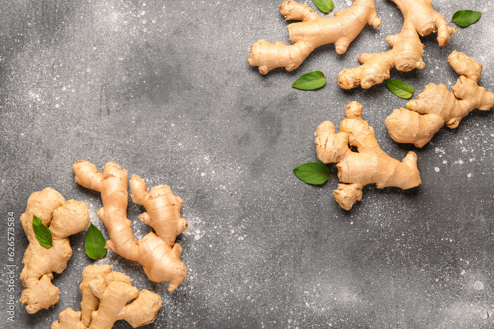 Fresh ginger roots and leaves on grey background