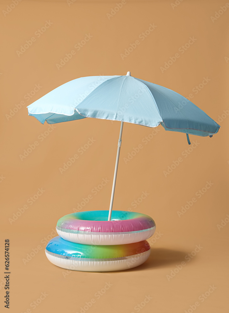 Swim rings with beach umbrella on beige background