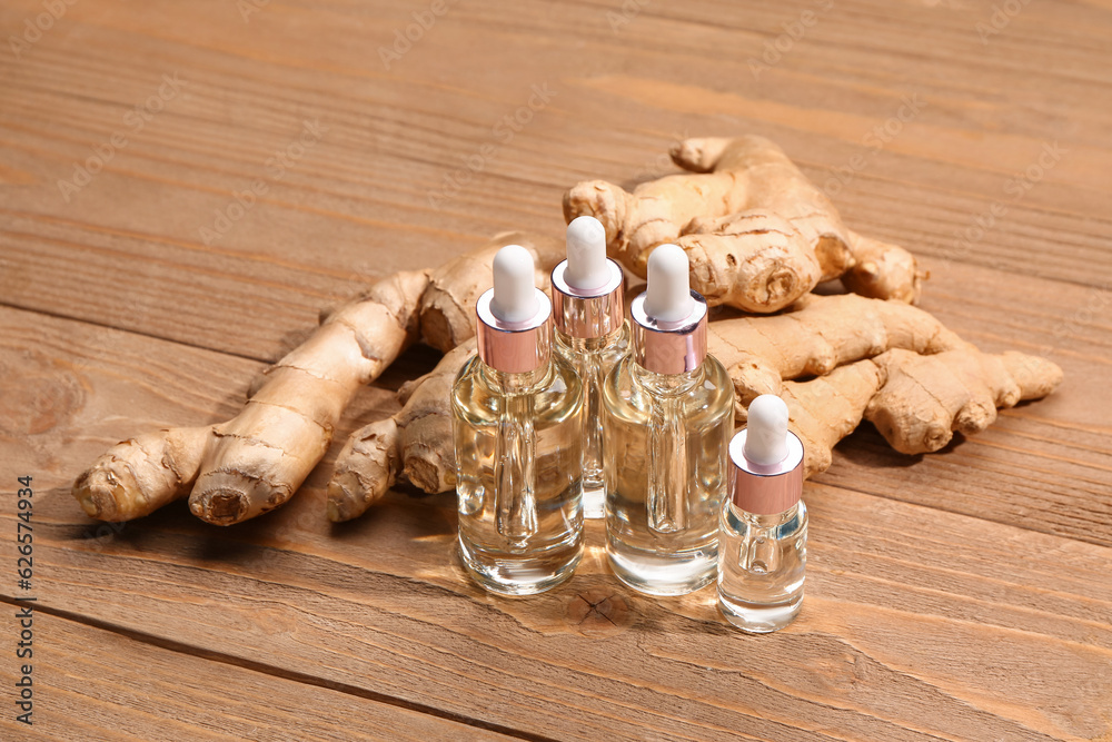 Bottles of ginger cosmetic oil on wooden background