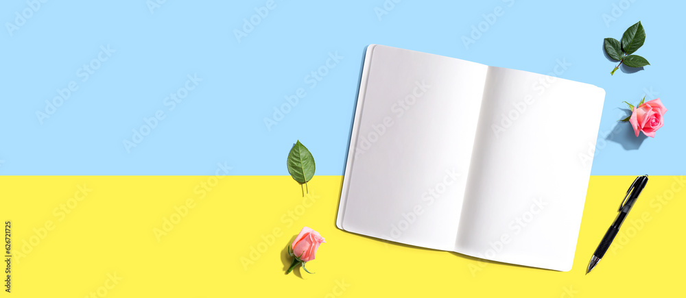 Open notebook or diary with a pen from above with rose buds- flat lay