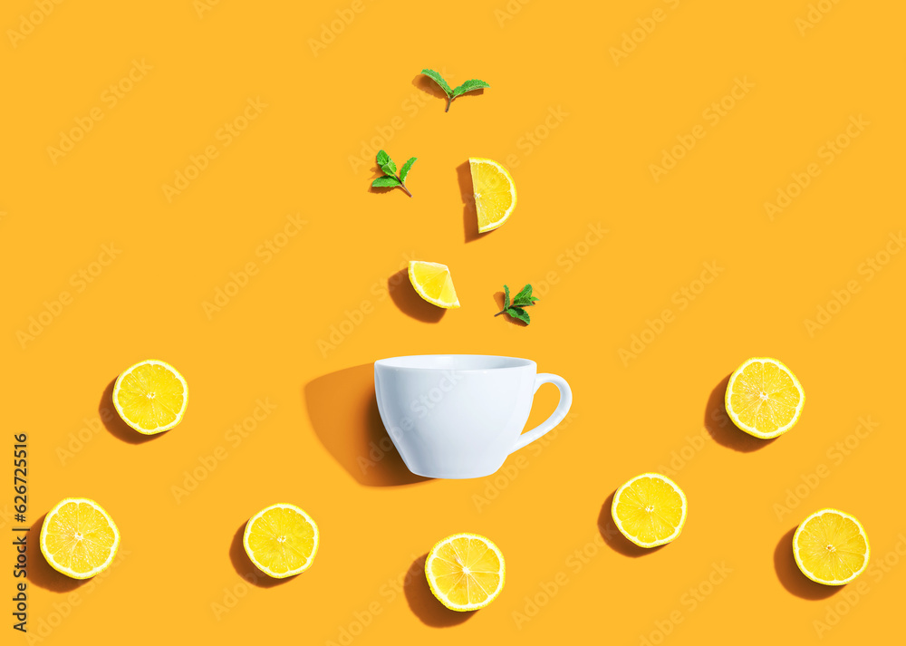 Fresh yellow lemons with tea cup overhead view - flat lay