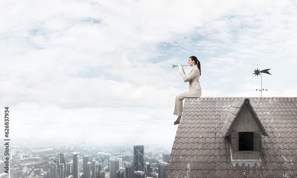 Beautiful young woman playing trumpet on roof