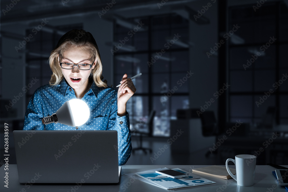 Attractive blonde wearing glasses in dark office using laptop. Mixed media