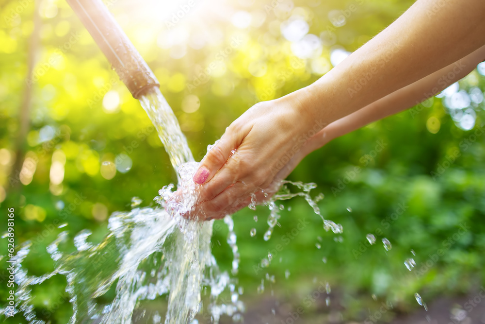 Close up view of womans hands in natural source of water in the park.