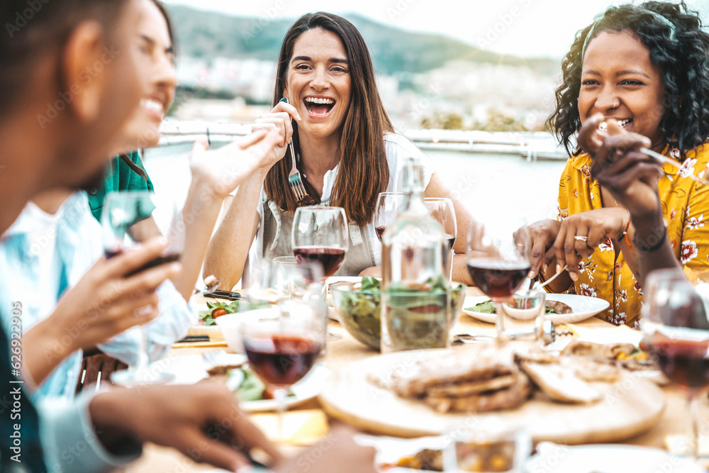 Multiethnic friends having fun at rooftop bbq dinner party - Group of young people diner together si