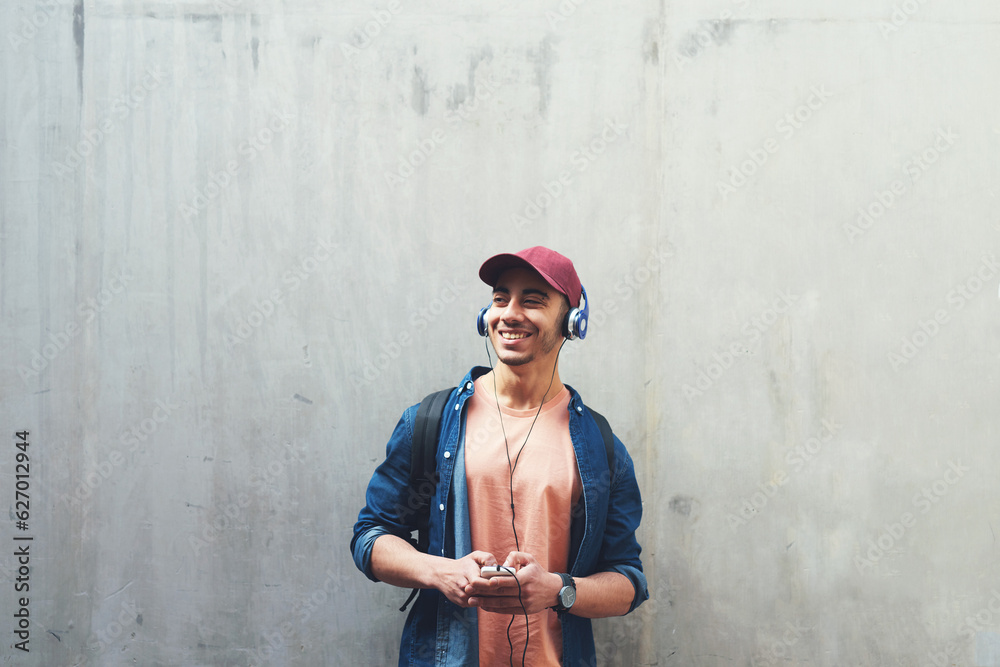 Man, listening and music with smile in outdoor with concrete wall background for entertainment. Happ