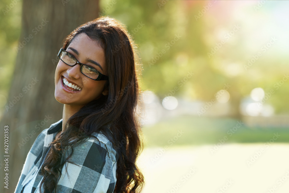 Casual charm. A beautiful ethnic woman standing in a park wearing glasses.