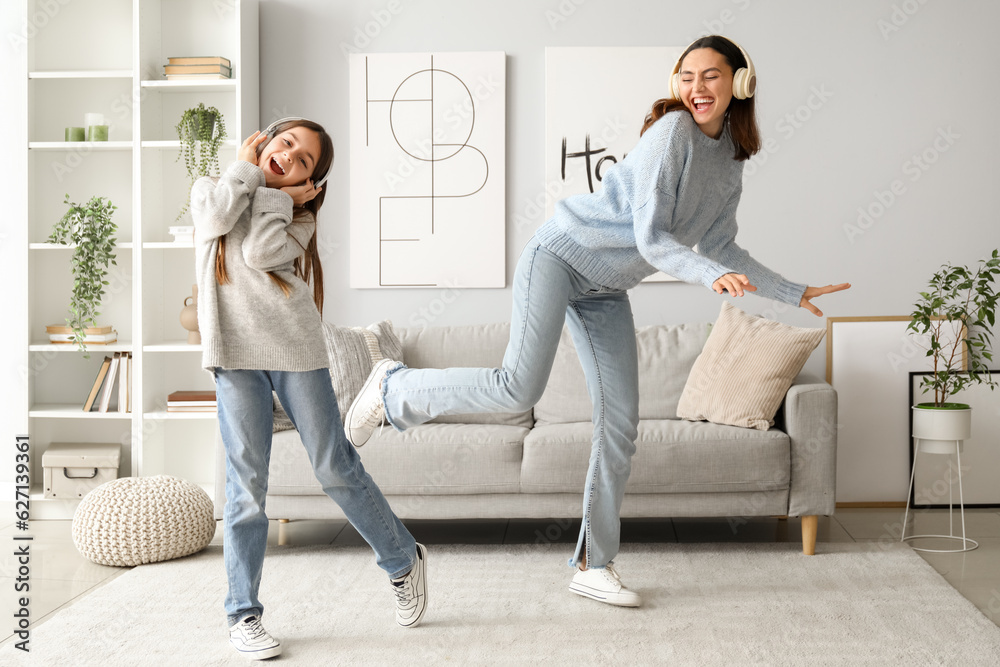 Little girl and her mother in sweaters and headphones dancing at home