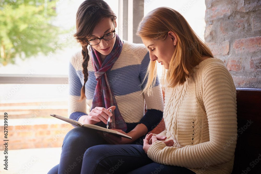 Preparing for an upcoming test. Shot of two university students looking through some notes together 